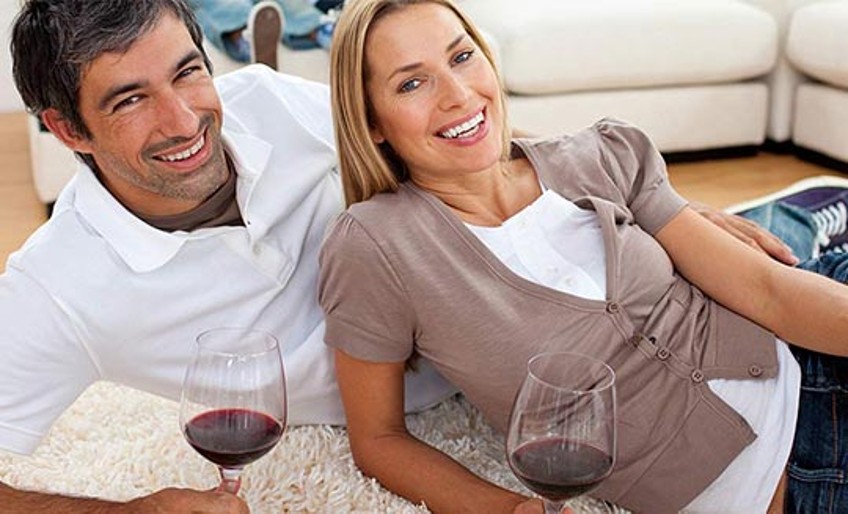 Haftpflichtversicherung - Paar mit Rotweingläsern auf Teppich